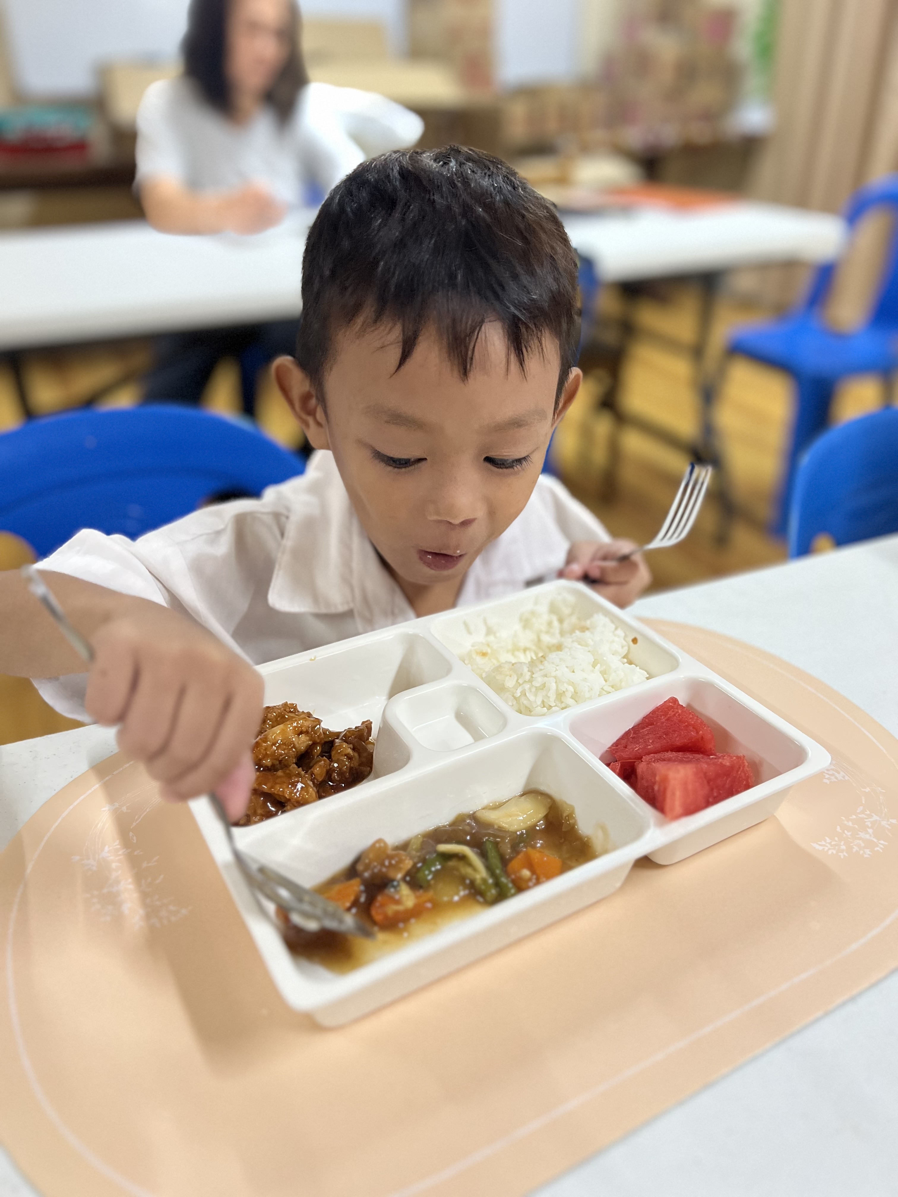 A young boy eagerly eating his vegetables and rice.
