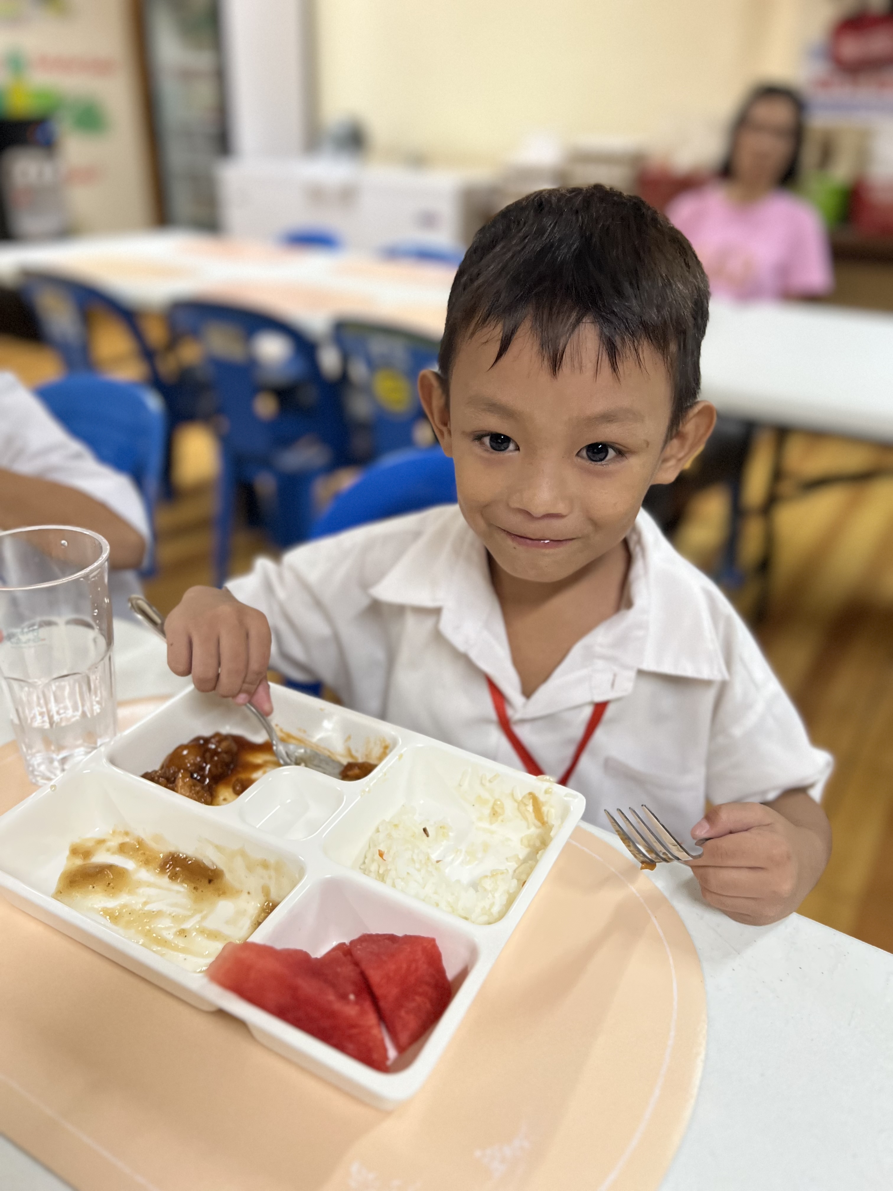 A happy child looking at the camera after finishing most of his meal.