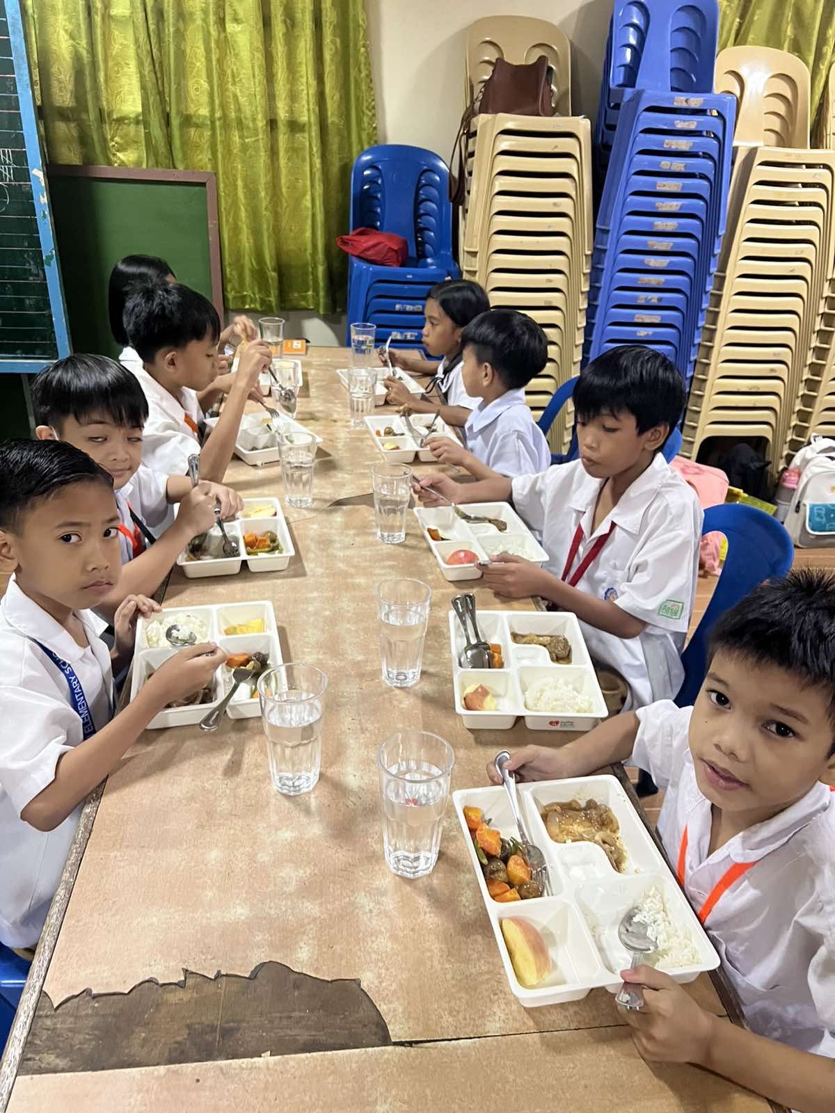 Children in school uniforms happily eating their complete meals