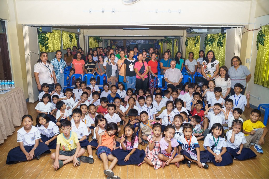 A large group of school children in uniforms and adults gathered together in a hall for the Feeding Futures PH school year kick-off.