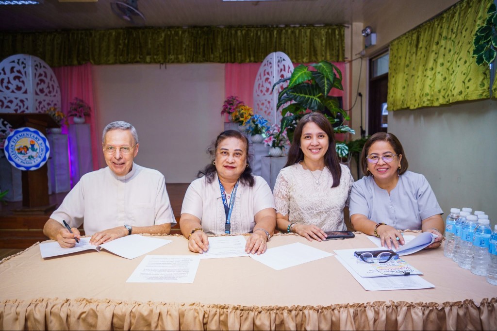 Partners seated at a table signing documents to formalize the Feeding Futures PH program for the new school year.
